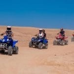 Quad biker navigating through the Agafay Desert, surrounded by rocky terrain and scenic landscapes.